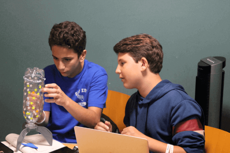 Two young engineering summer school students building a water bottle rocket Two young engineering summer school students building a water bottle rocket