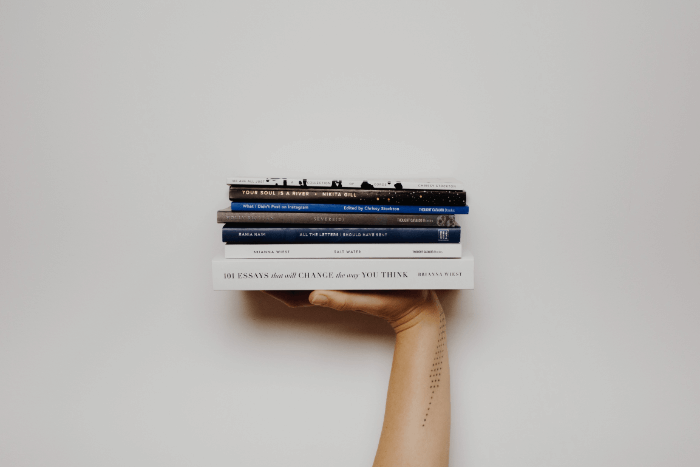 A student holding up books to learn how to write for a living A student holding up books to learn how to write for a living
