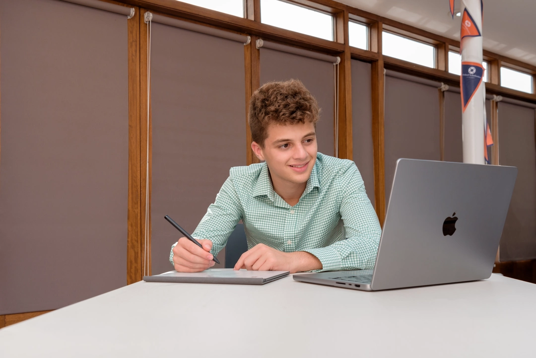 Oxford Scholastica student looking into a laptop and smiling