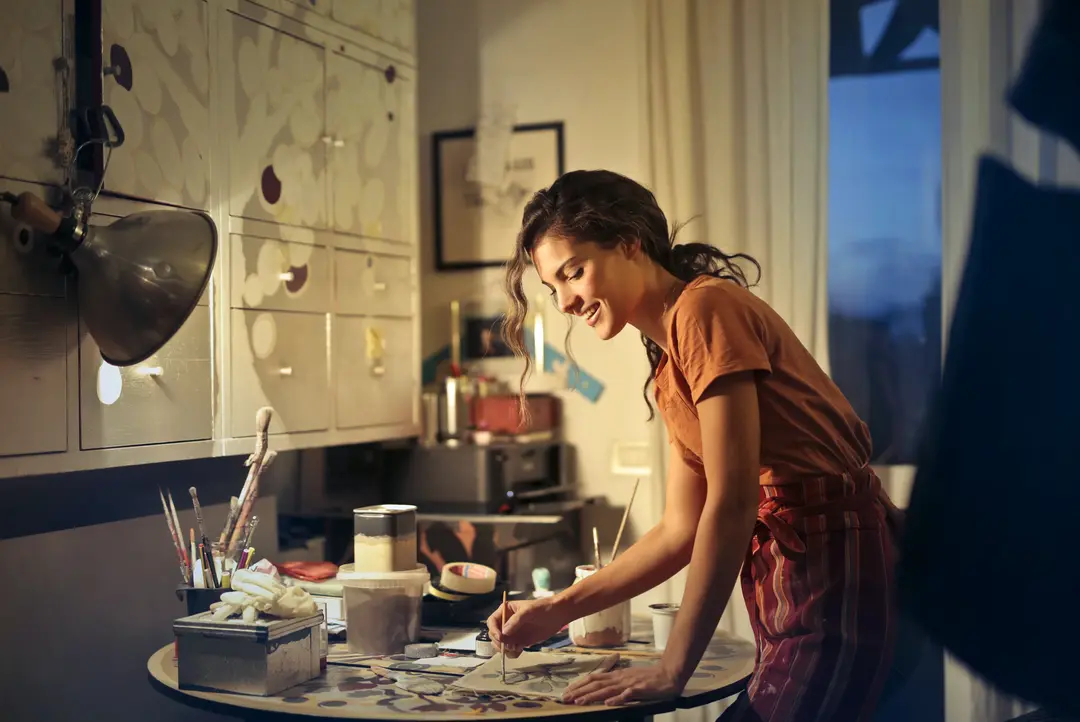 Artist painting by their work station, smiling